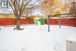 Snowy yard featuring a storage shed and a fenced backyard - 