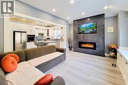 Living area featuring a tiled fireplace, light wood-style floors, lofted ceiling, and recessed lighting - 