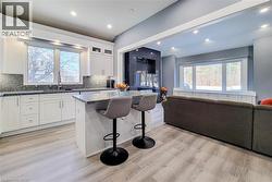 Kitchen featuring a kitchen bar, white cabinetry, a kitchen island, open floor plan, and recessed lighting - 