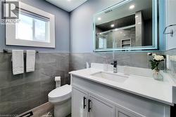 Bathroom with a shower stall, vanity, tile walls, recessed lighting, and wood finished floors - 