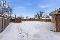 Yard covered in snow featuring a fenced backyard and a storage shed - 
