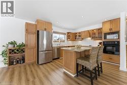 Kitchen with open shelves, appliances with stainless steel finishes, light stone counters, and a breakfast bar area - 