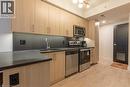 Kitchen featuring modern cabinets, appliances with stainless steel finishes, light brown cabinetry, and decorative backsplash - 145 Columbia Street W Unit# 1034, Waterloo, ON  - Indoor Photo Showing Kitchen 