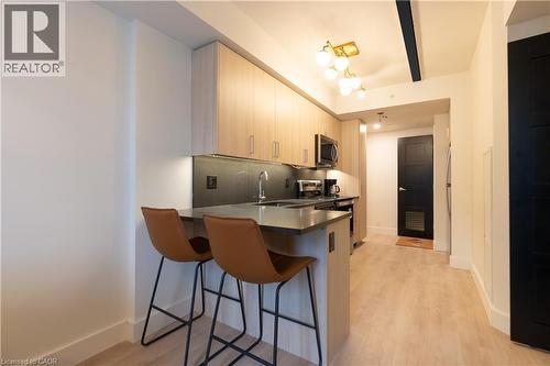 Kitchen featuring a kitchen breakfast bar, dark countertops, a peninsula, backsplash, and stainless steel appliances - 145 Columbia Street W Unit# 1034, Waterloo, ON - Indoor Photo Showing Kitchen