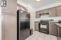 Kitchen featuring black appliances, under cabinet range hood, light tile patterned floors, and a textured ceiling - 