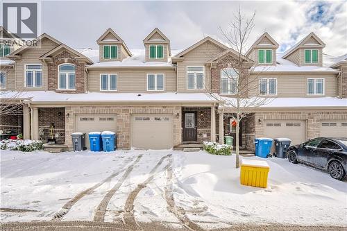 View of front facade featuring an attached garage, stone siding, and covered porch - 23 Kingsbury Square Unit# 23, Guelph, ON - Outdoor With Facade