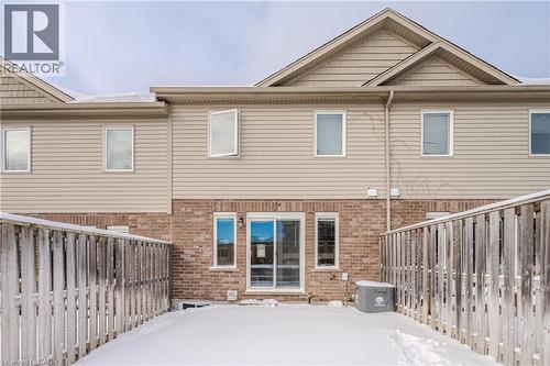 Snow covered property with brick siding and a fenced backyard - 23 Kingsbury Square Unit# 23, Guelph, ON - Outdoor With Exterior