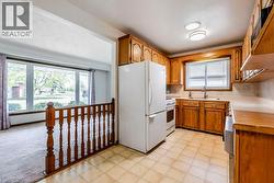 Kitchen featuring white appliances, a sink, brown cabinetry, and plenty of natural light - 