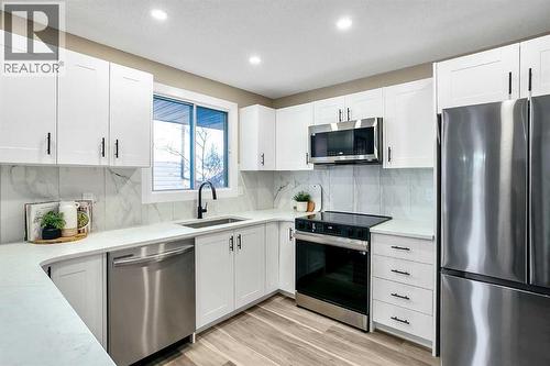 Kitchen has been updated with timeless white shaker cabinets, brand new stainless steel appliances & quartz counters - 467 Berkley Crescent Nw, Calgary, AB - Indoor Photo Showing Kitchen With Upgraded Kitchen
