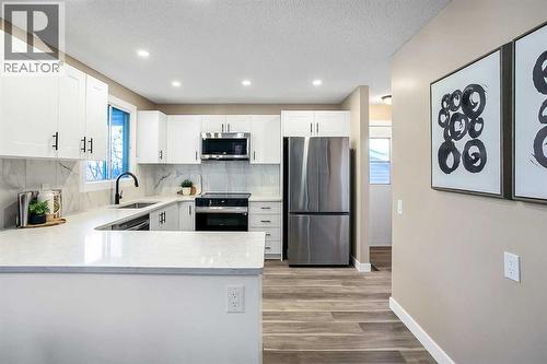 Kitchen has been updated with timeless white shaker cabinets, brand new stainless steel appliances & quartz counters - 467 Berkley Crescent Nw, Calgary, AB - Indoor Photo Showing Kitchen With Upgraded Kitchen