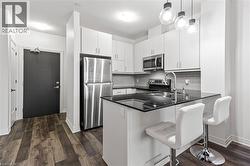 Kitchen featuring appliances with stainless steel finishes, a peninsula, dark countertops, backsplash, and pendant lighting - 