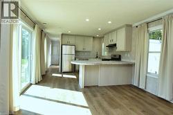 Kitchen featuring a peninsula, stainless steel appliances, dark wood-style floors, recessed lighting, and under cabinet range hood - 