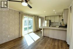 Kitchen featuring light countertops, dark wood finished floors, appliances with stainless steel finishes, a peninsula, and crown molding - 