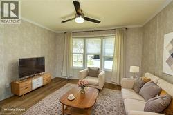 Living area with crown molding, wood finished floors, and a ceiling fan - 
