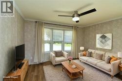 Living room featuring dark wood-type flooring, ornamental molding, and a ceiling fan - 