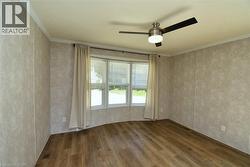 Spare room featuring dark wood-style flooring, crown molding, and a ceiling fan - 