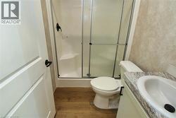 Bathroom with a stall shower, vanity, and dark wood-style flooring - 
