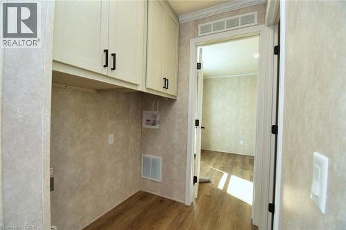 Laundry area with cabinet space, dark wood-type flooring, ornamental molding, and hookup for a washing machine - 1085 Concession 10 Road W Unit# 23, Flamborough, ON - Indoor Photo Showing Other Room