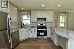 Kitchen featuring stainless steel appliances, a peninsula, dark wood-style floors, exhaust hood, and recessed lighting - 