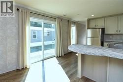 Kitchen featuring appliances with stainless steel finishes, crown molding, dark wood-type flooring, a peninsula, and light stone countertops - 