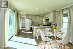 Kitchen featuring a peninsula, freestanding refrigerator, electric stove, light wood finished floors, and a breakfast bar area - 