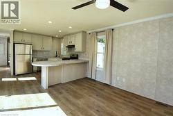 Kitchen featuring stainless steel appliances, dark wood finished floors, a peninsula, crown molding, and a ceiling fan - 