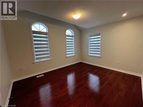 Empty room with a textured ceiling, dark wood finished floors, vaulted ceiling, and healthy amount of natural light - 24 Hazelton Avenue, Hamilton, ON - Indoor Photo Showing Other Room