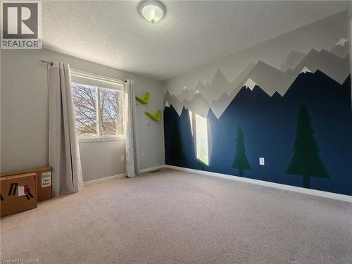 Unfurnished room with light carpet, a textured ceiling, and an accent wall - 563 Dansbury Drive, Waterloo, ON 