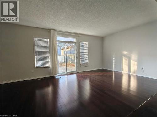 Spare room featuring a textured ceiling and dark wood finished floors - 563 Dansbury Drive, Waterloo, ON 