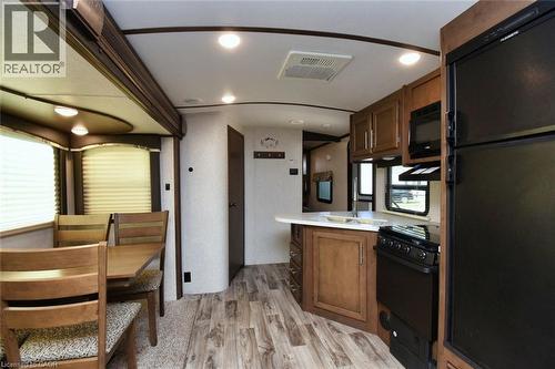 Kitchen with black appliances, light countertops, a peninsula, light wood-style floors, and brown cabinetry - 1085 10Th Concession Road W Unit# 29, Flamborough, ON - Indoor