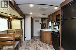 Kitchen with black appliances, light countertops, a peninsula, light wood-style floors, and brown cabinetry - 