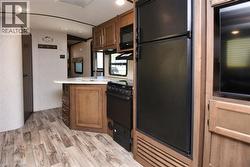 Kitchen featuring black appliances, light wood finished floors, light countertops, a peninsula, and brown cabinets - 