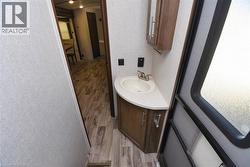 Half bathroom featuring light wood finished floors, vanity, and a textured wall - 