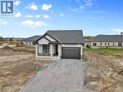 Modern inspired farmhouse featuring a porch, an attached garage, stucco siding, and gravel driveway - 