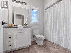 Bathroom featuring toilet, baseboards, curtained shower, and vanity - 