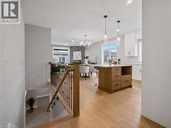 Kitchen featuring light wood-type flooring, light countertops, white cabinetry, a chandelier, and hanging light fixtures - 