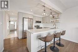 Kitchen with stainless steel appliances, decorative light fixtures, a peninsula, a breakfast bar area, and open shelves - 