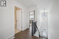 Hall with an upstairs landing and dark wood-type flooring - 