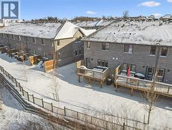 Snow covered property with brick siding and a wooden deck - 