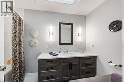 Bathroom with vanity, shower / tub combo with curtain, light marble finish floors, and a skylight - 