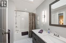 Bathroom with shower / bath combo with shower curtain, vanity, light marble finish flooring, recessed lighting, and a skylight - 