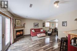 Living area featuring a warm lit fireplace, wainscoting, plenty of natural light, and dark wood-style floors - 