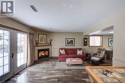 Living room with a wainscoted wall, a glass covered fireplace, french doors, and wood finished floors - 