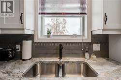 Kitchen view of white cabinetry, tasteful backsplash, and light stone counters - 