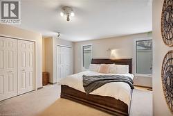 Bedroom with light colored carpet, two closets, and multiple windows - 