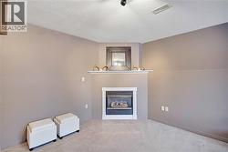Unfurnished living room featuring a glass covered fireplace, carpet flooring, and a textured ceiling - 