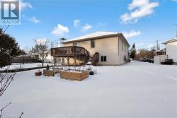 Snow covered house featuring stairway and a wooden deck - 