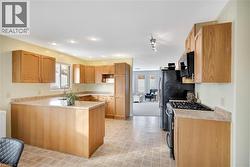 Kitchen featuring stainless steel gas range, light countertops, plenty of natural light, a peninsula, and recessed lighting - 