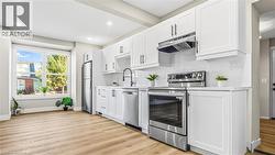 Kitchen featuring white cabinets, stainless steel appliances, light wood finished floors, backsplash, and recessed lighting - 