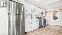 Kitchen featuring appliances with stainless steel finishes, light countertops, white cabinetry, light wood finished floors, and recessed lighting - 